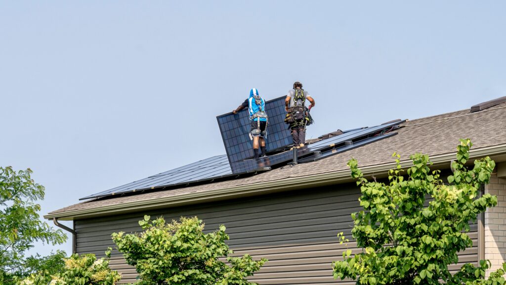 Workers are installing solar panels onto a roof.