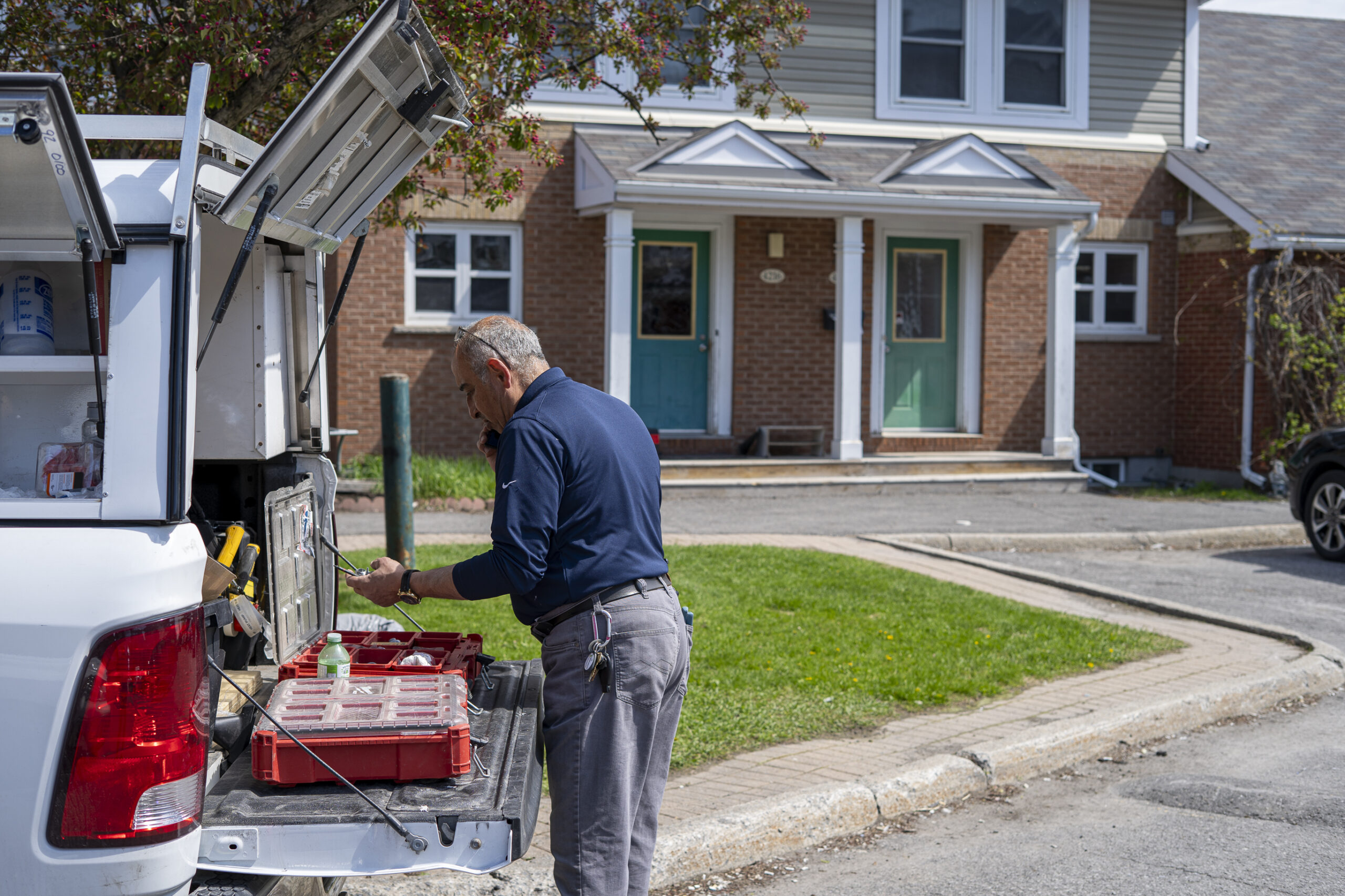 A person stands beside a 1Click truck with the back and sides of the truck open. Various tools and other items are visible.